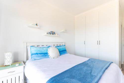 a white bedroom with a blue and white bed at Ocean View Escape with Private Rooftop -Sancta Maria in Kingsburgh