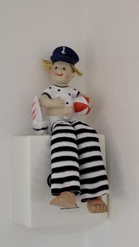 a doll sitting on a shelf holding a cup at "Sunny" in Burgtiefe auf Fehmarn 