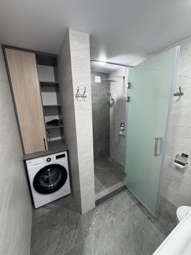 a bathroom with a washing machine and a shower at Cozy Apartment in the Heart of Fergana in Fergana