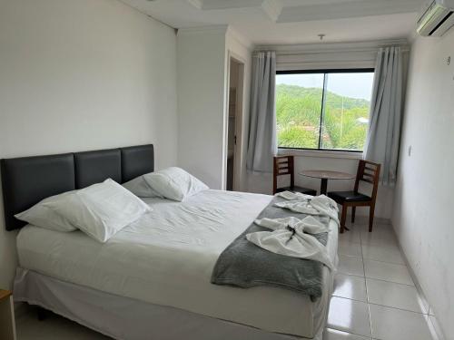 a bedroom with a bed and a table and a window at Pousada Paulett's - Hospedagem na Zona Norte de Ilhéus - Bahia in Ilhéus