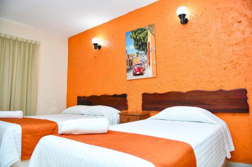 three beds in a room with an orange wall at Hotel Uxulkah in Campeche