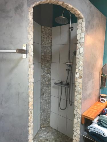 La salle de bains est pourvue d'une douche et d'un mur en pierre. dans l'établissement Maison Studio près de Montpellier, à Teyran