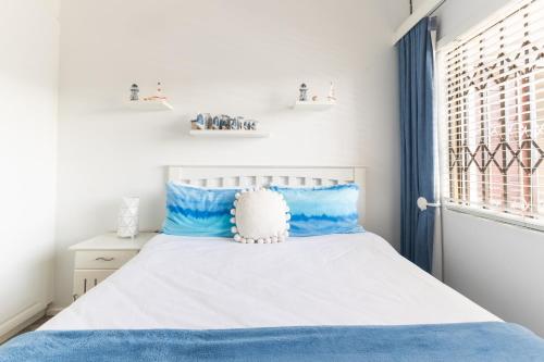 a bedroom with a white bed with blue pillows at Ocean View Escape with Private Rooftop -Sancta Maria in Kingsburgh
