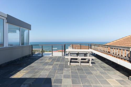 a balcony with a picnic table and the ocean at Ocean View Escape with Private Rooftop -Sancta Maria in Kingsburgh