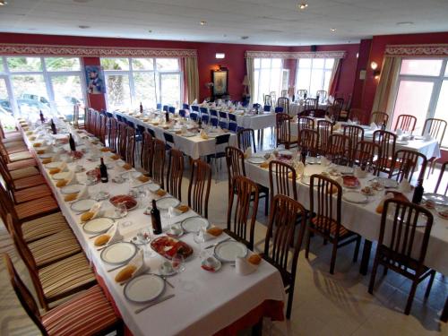 a dining room filled with tables and chairs with food at Hotel Azpiazu in Muros de Nalón