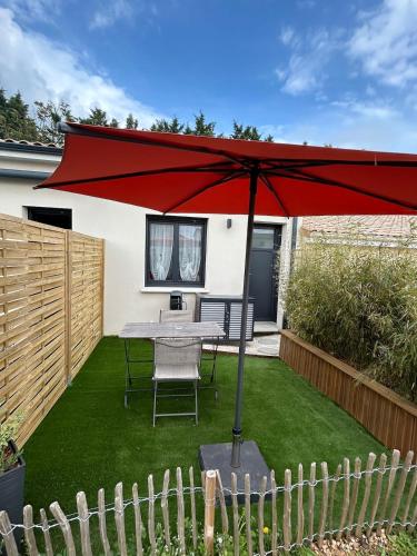 un parasol rouge sur une pelouse avec une table dans l'établissement Studio avec jardinet, à Chasseneuil-du-Poitou