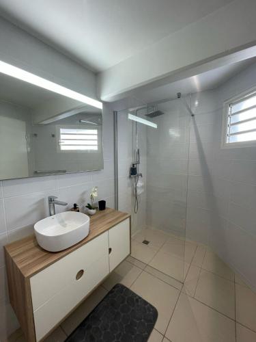 a white bathroom with a sink and a shower at Le Nid d'Amour Créole - Studio romantique avec accès au lagon et à la piscine XXL de 1 000 m2 - Saint-François in Saint-François