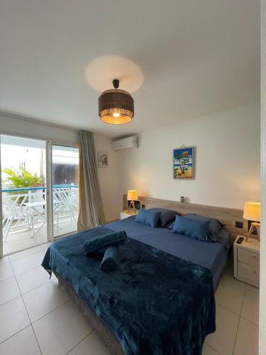 a bedroom with a large bed and a balcony at Le Nid d'Amour Créole - Studio romantique avec accès au lagon et à la piscine XXL de 1 000 m2 - Saint-François in Saint-François
