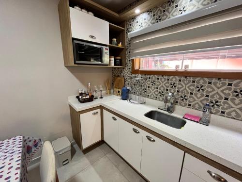 a small kitchen with a sink and a microwave at Casa Aconchego Canto da Viola in São Roque