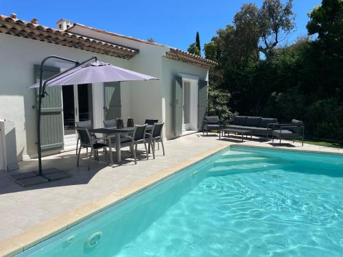 une piscine avec une table, des chaises et un parasol dans l'établissement Villa Sainte Maxime 8 personnes piscine privée et proche de la mer, à Sainte-Maxime