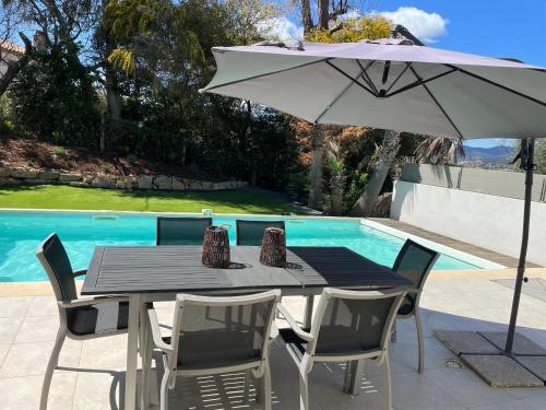 une table et des chaises avec un parasol à côté d'une piscine dans l'établissement Villa Sainte Maxime 8 personnes piscine privée et proche de la mer, à Sainte-Maxime