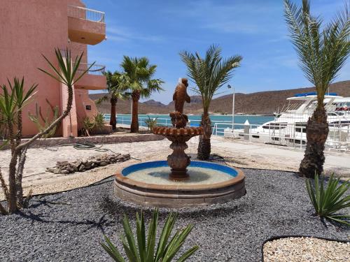 a fountain in a courtyard with palm trees and a building at Econo Beach Cantamar in La Paz