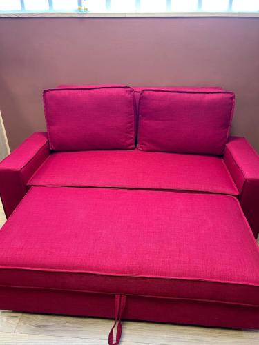 a red couch with pink cushions in a room at Charmant appartement Havana in Carhaix-Plouguer
