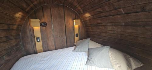 a bed in a wooden room with two pillows at Barrels by the Lake in Priles