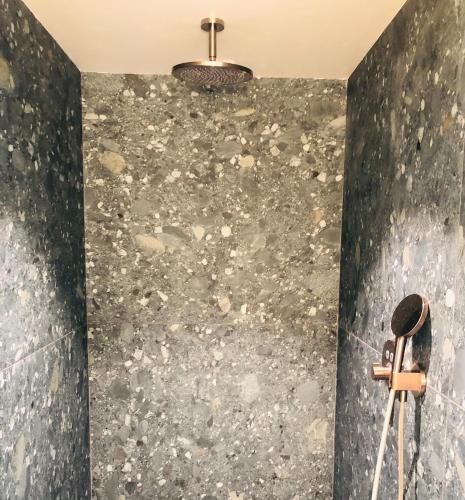 a bathroom with a stone wall with a chandelier at L'Orée de Borzée in La Roche-en-Ardenne