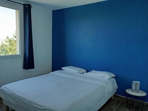 - une chambre bleue dotée d'un lit avec un mur bleu dans l'établissement Santorini du Futuroscope, à Chasseneuil-du-Poitou
