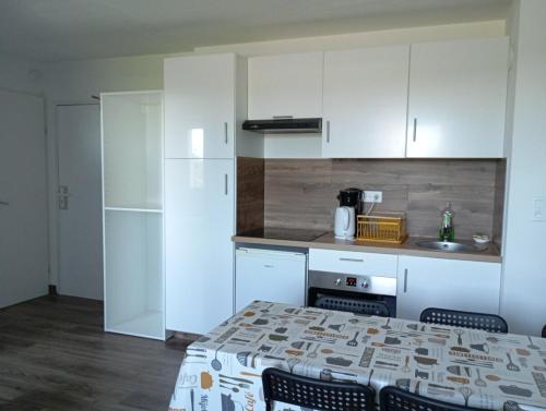 une cuisine avec des armoires blanches et une table et des chaises dans l'établissement Santorini du Futuroscope, à Chasseneuil-du-Poitou