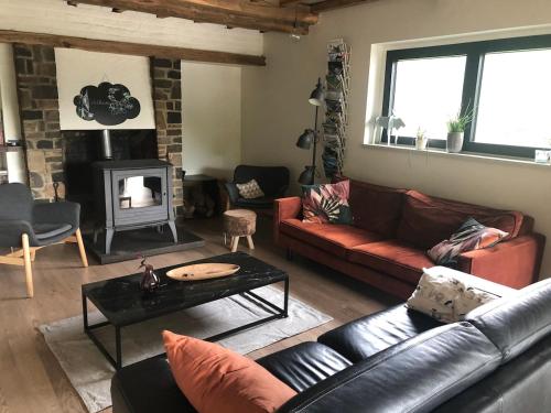 a living room with a leather couch and a fireplace at L'Orée de Borzée in La Roche-en-Ardenne