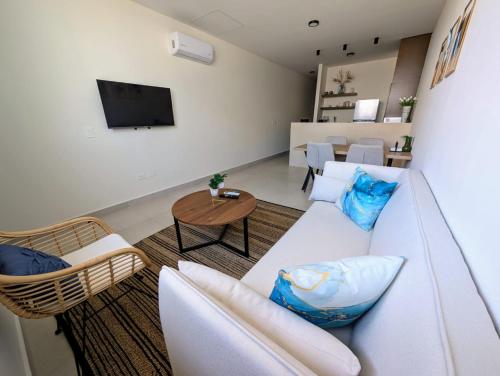 a living room with a white couch and a table at Makech Montebello by Kanaa in Mérida