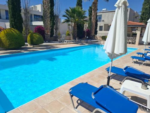 a swimming pool with chairs and an umbrella at Sunset Green 01 in Paphos City