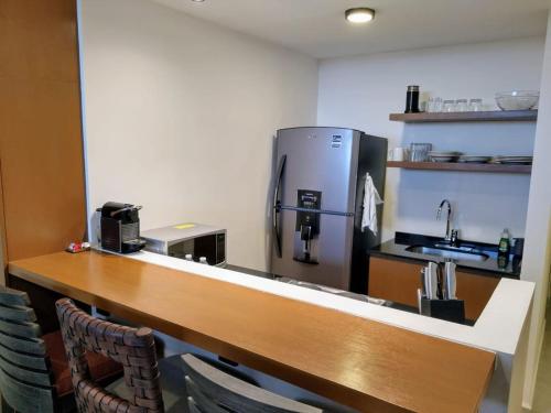 a kitchen with a refrigerator and a counter with chairs at Encanto de Montebello in Mérida