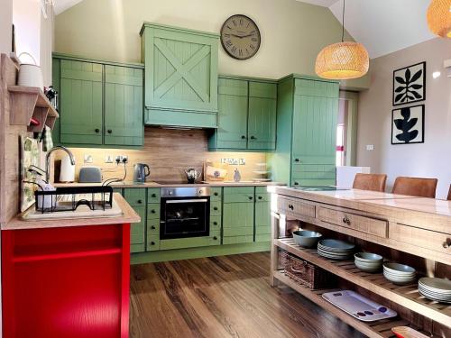 a kitchen with green cabinets and a clock on the wall at Summerhill Byre in Ballymena