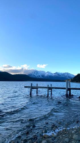 a dock in a body of water with snow covered mountains at Departamento Río Blanco in Cholila