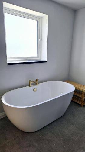 a white bath tub in a bathroom with a window at Benji & Milo's Farmhouse in Hillhead