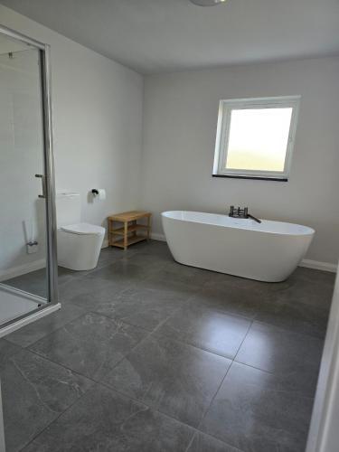 a white bathroom with a tub and a toilet at Benji & Milo's Farmhouse in Hillhead