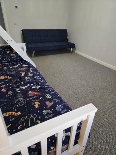 a bedroom with a bed and a blue couch at Benji & Milo's Farmhouse in Hillhead