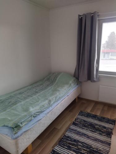 a bed in a room with a window and a rug at Lägenhet Lappfjärd in Lapväärtti
