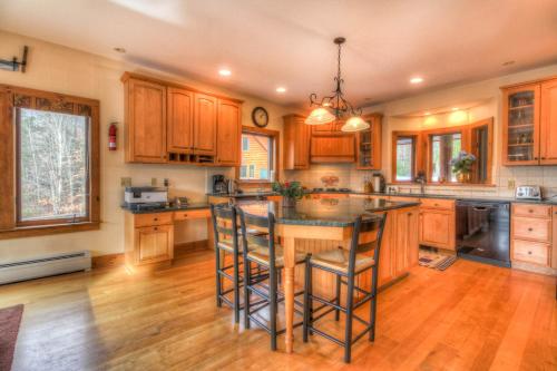 a kitchen with wooden cabinets and a island with bar stools at Most Luxury 7000 Sq ft Log Estate with Pool Hot Tub Sauna in Wilmington
