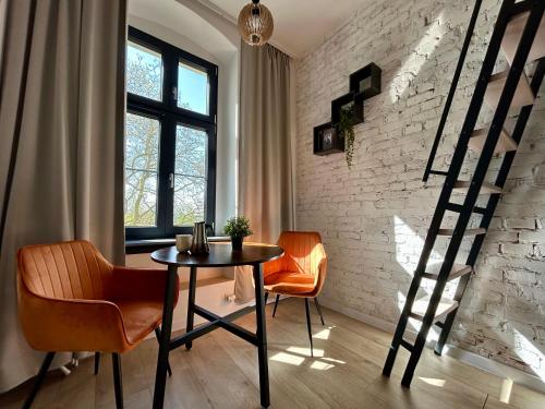 a dining room with a table and chairs and a brick wall at Loft Apartments Gliwice in Gliwice