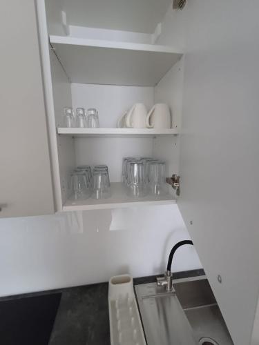 a kitchen with a shelf with glasses and a sink at Apartament przy Armii Krajowej I in Kluczbork