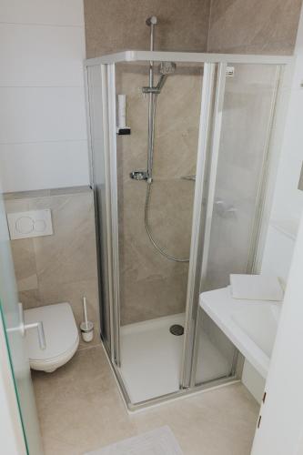 a bathroom with a shower with a toilet and a sink at Pension Kinzl mit E-Ladestation in Offenhausen