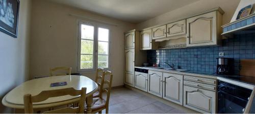- une cuisine avec une table, une table et des chaises dans l'établissement Maison en bord de mer, à Grandcamp-Maisy