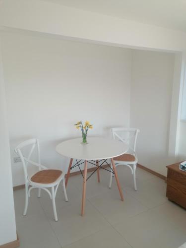 a white table and chairs with a vase of flowers on it at The Croft in Whale Islet