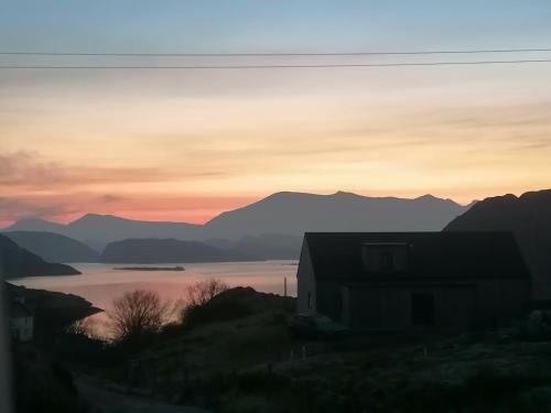 a house on a hill next to a lake at sunset at The Croft in Whale Islet