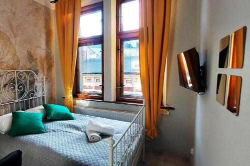 Un dormitorio con una cama con almohadas verdes y una ventana. en Cozy Old Town Apartments, en Cracovia
