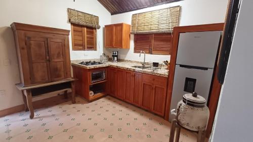 une cuisine avec des armoires en bois et un réfrigérateur dans l'établissement Lovely Cottage at La Ropa Beach, à Zihuatanejo