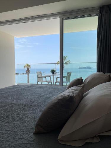 a bedroom with a bed with pillows and a view of the ocean at Harbour Lights Studio Apartments in Paphos City
