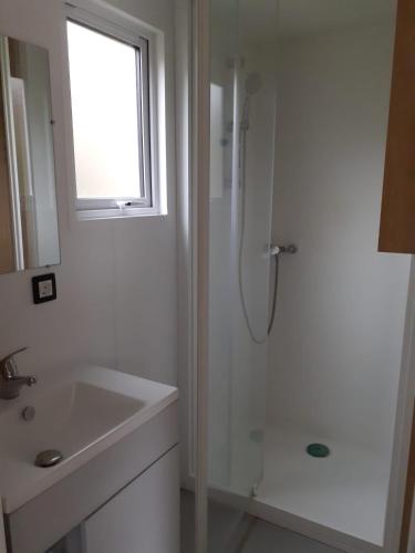 une salle de bain blanche avec une douche et un lavabo dans l'établissement Camping municipal du Moulin Horte sud Aveyron, à Plaisance