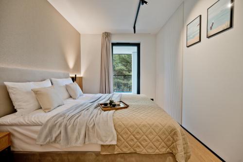 a bedroom with a large white bed with a window at Apartamenty Wydma & Las BlueApart in Jastarnia