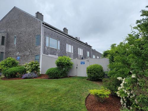 a house with a white fence and a yard at Spacious Oceanfront 3BR Condo with Private Beach in Ideal Hyannis Location in Barnstable