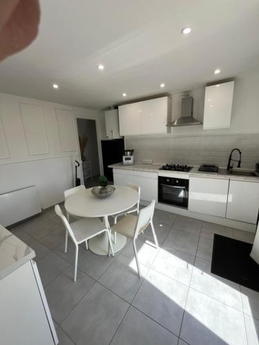 una cucina bianca con tavolo e sedie bianchi di Maison appartement 54m2 a Varennes-Vauzelles