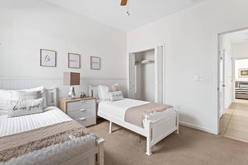 a white bedroom with two beds and a mirror at Ground Floor Gathering up to 9 guests BL387 in Kissimmee