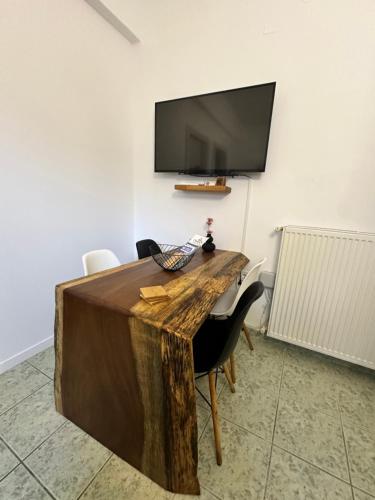 a wooden table with chairs and a television on a wall at Le Rocher 2 in Ermoupoli