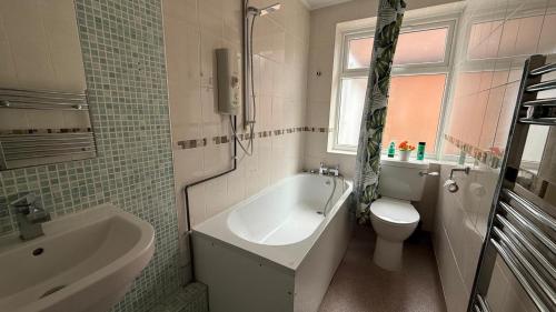 a bathroom with a tub and a toilet and a sink at Stunning 3 Bedroom 2 Bathroom Bungalow by CozyNest in Earley