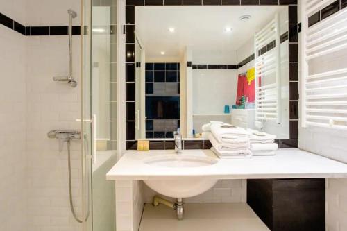 une salle de bain blanche avec un lavabo et une douche dans l'établissement Hidden beauty - Calm & Verdant - Orsay Museum, à Paris