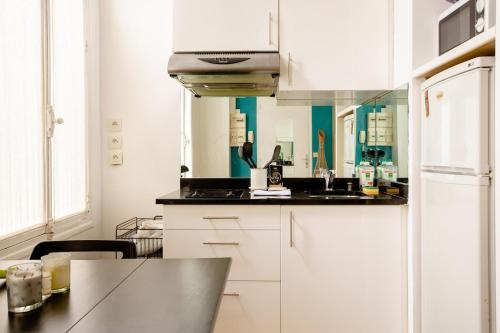 une cuisine avec des armoires blanches et un comptoir noir dans l'établissement Hidden beauty - Calm & Verdant - Orsay Museum, à Paris